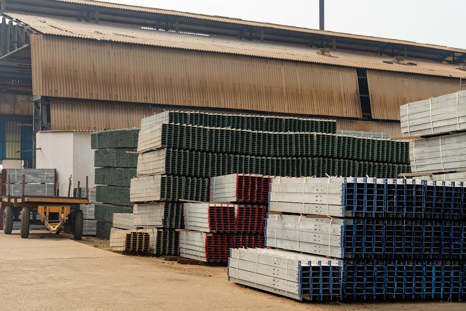 Outdoor view of an industrial warehouse with multiple stacks of metal beams and pallets.